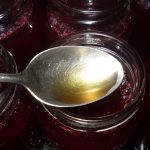 Gläser mit dunkelrotem Johannisbeer-Fruchtaufstrich, ein Löffel liegt darüber