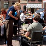 Kellnerin bedient Gäste auf einer Café-Terrasse – typischer Minijob in der Gastronomie