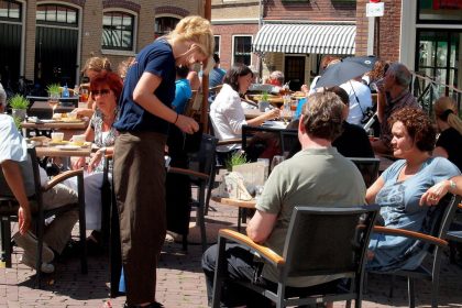 Kellnerin bedient Gäste auf einer Café-Terrasse – typischer Minijob in der Gastronomie