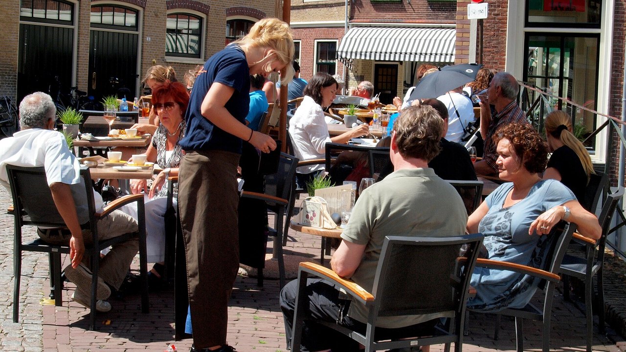 Kellnerin bedient Gäste auf einer Café-Terrasse – typischer Minijob in der Gastronomie