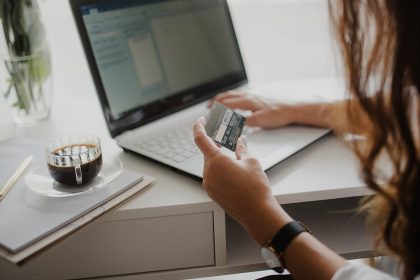 Frau mit Kreditkarte vor einem Laptop beim Online-Einkauf