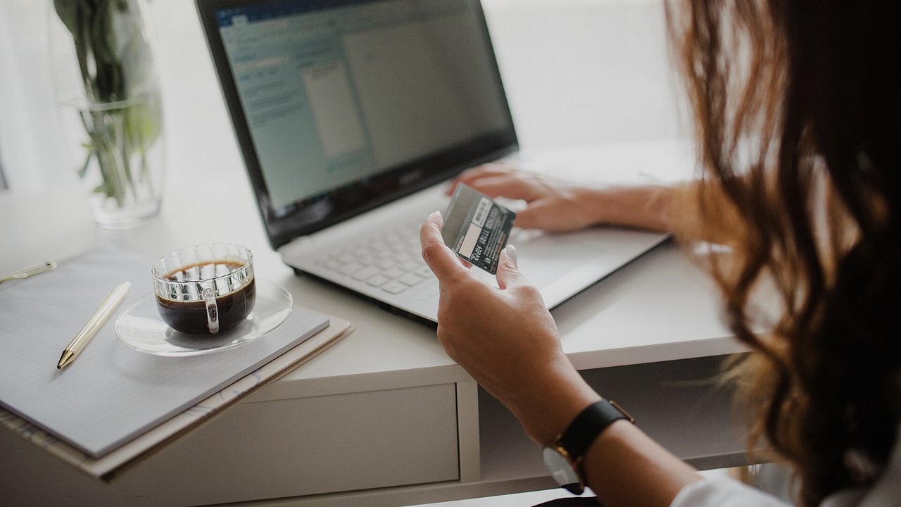 Frau mit Kreditkarte vor einem Laptop beim Online-Einkauf